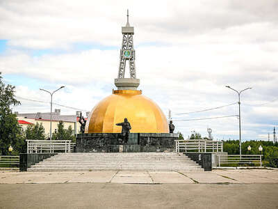 Мемориал «Первопроходцам».
Геолог, нефтяник и строитель – три собирательных образа специалистов стали основными фигурами Мемориала первопроходцам, что был установлен в Мегионе в 2003 году.
Ведь люди именно этих трёх профессий стояли у истоков освоения нашего края как основного нефтяного добытчика в России. Первыми сюда высадились геологи. После разведки приехали нефтяники. А за ними – строители, чтобы возводить дома и прокладывать железную дорогу.
Мемориал с глубокой смысловой нагрузкой был спроектирован местным архитектором Г. И. Бойко. Найти его творение можно на набережной реки Меги.
Фигуры основоположников нефтяной отрасли в Югре размещены вокруг огромного золотого купола. Он – не что иное, как символ нефти. Капля «черного золота» стоит на высоком пьедестале. На нем изображены птицы, звери и рыбы – ведь наш край богат не только полезными ископаемыми. В тайге кроется огромное природное богатство. Венчает композицию нефтяная вышка с гербом Мегиона с черным соболем – также символом нефтегазодобывающего и пушного богатства. С другой стороны купола можно увидеть карту, на которой отмечен Мегион.
Обязательно посмотрите интересный памятник, если будете в Мегионе.